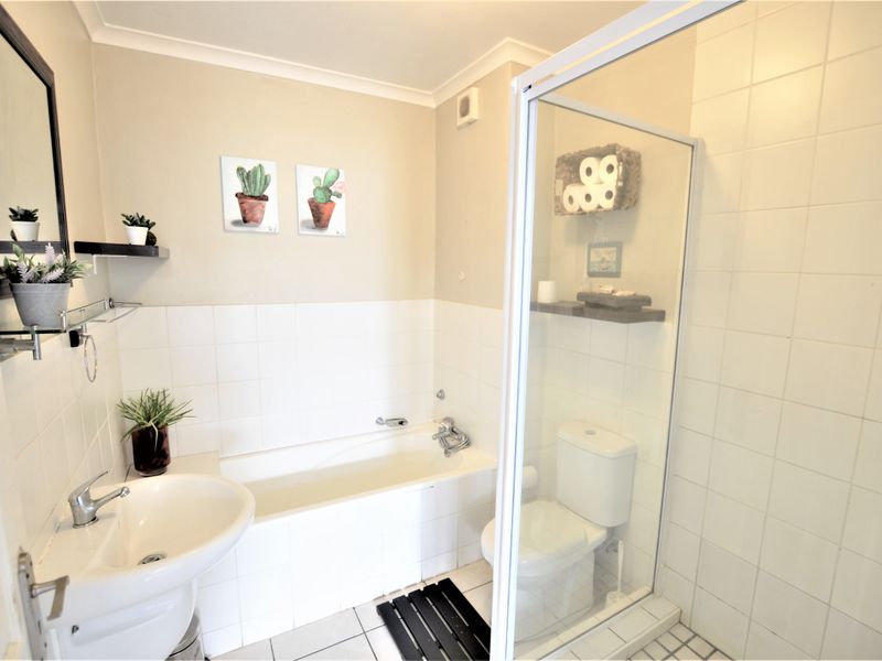 A functional bathroom featuring a pedestal basin, built-in bathtub, and a separate shower enclosure with tiled finishes.