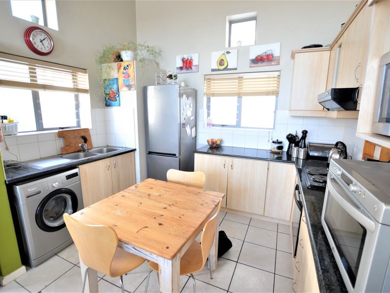 A functional kitchen featuring light wood cabinetry, granite countertops, tiled flooring, and integrated appliances including an oven and hob.