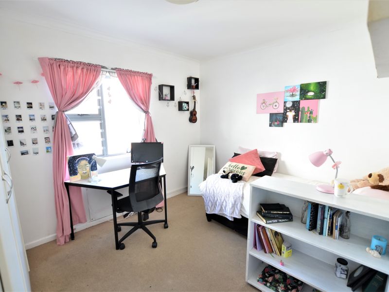 A functional bedroom featuring neutral carpeting, a built-in wardrobe, and a sliding window that provides natural light.