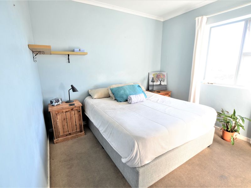 A standard bedroom featuring carpeted flooring, light blue walls, and a window allowing natural light into the space.