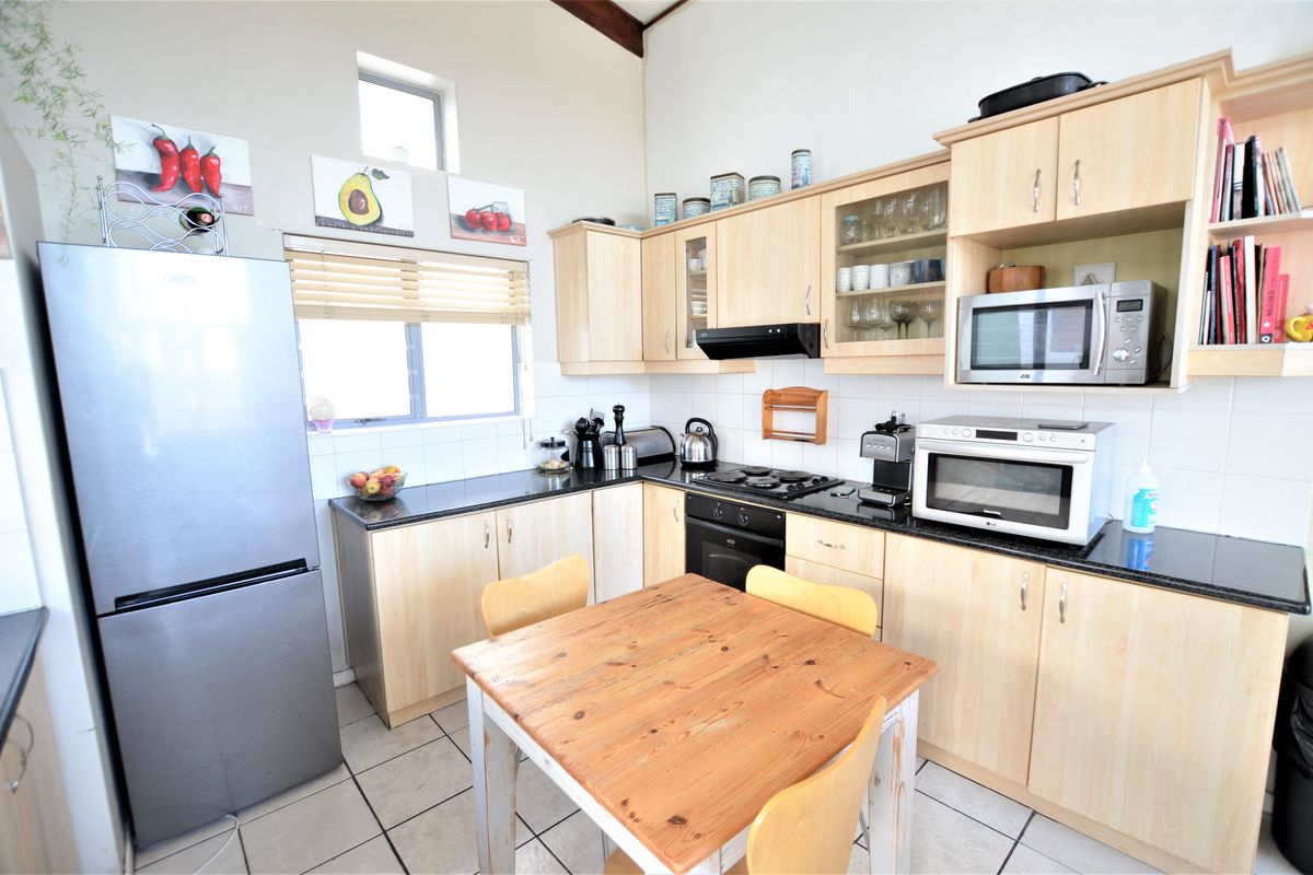 A functional kitchen featuring light wood cabinetry, granite countertops, built-in oven, gas hob, and tiled flooring with a bright, open layout.