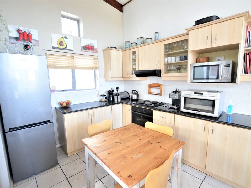 A functional kitchen featuring light wood cabinetry, granite countertops, built-in oven, gas hob, and tiled flooring with a bright, open layout.