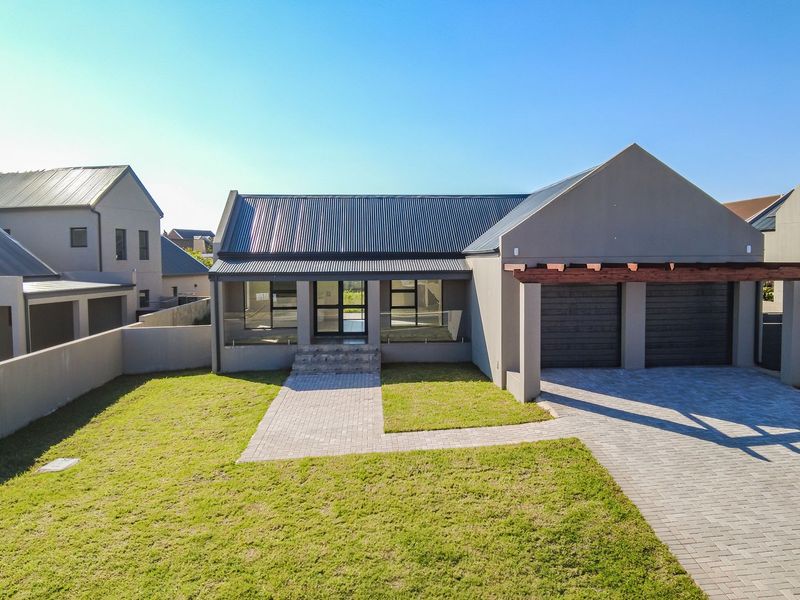 Modern single-story residence featuring a double garage, paved driveway, metal roof, and a welcoming entrance with glass balustrades and a timber pergola.