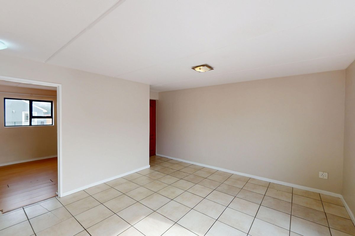 A bright, empty living area featuring neutral walls and ceramic tiled flooring, providing a versatile blank canvas for your interior design preferences.