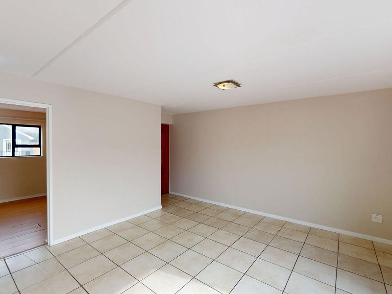A bright, empty living area featuring neutral walls and ceramic tiled flooring, providing a versatile blank canvas for your interior design preferences.