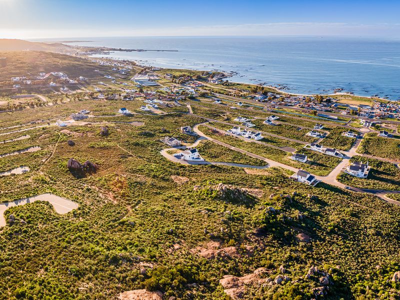 An aerial view of a coastal residential development featuring paved roads and established plots overlooking the ocean.