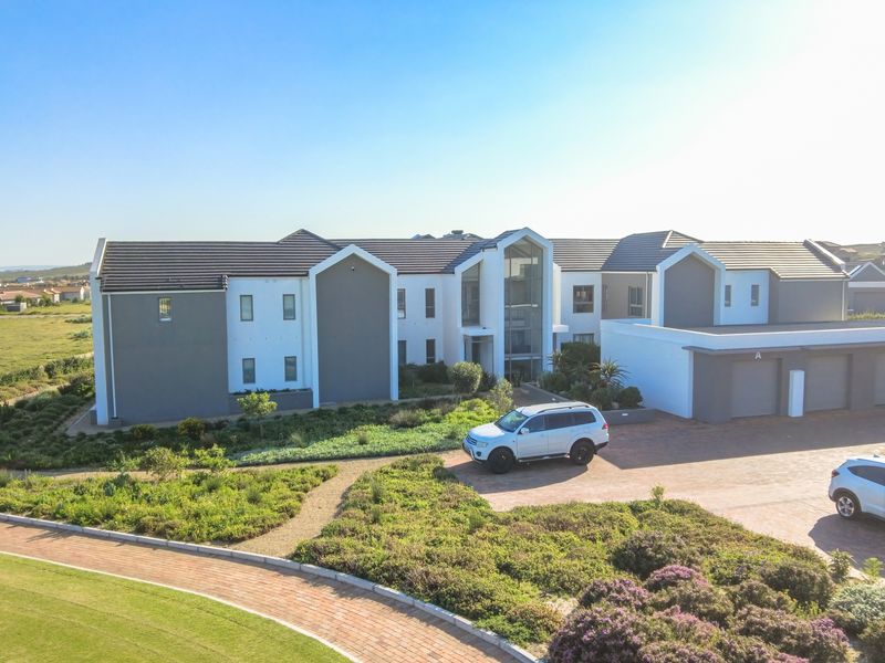 Aerial view of a modern townhouse complex featuring a paved driveway, multi-car garage, and well-maintained landscaped gardens.