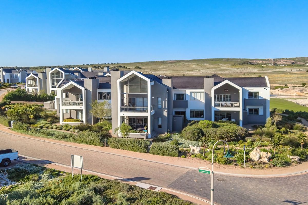 Aerial view of a modern townhouse complex featuring contemporary architectural design, tiled roofs, private balconies, and well-maintained landscaped gardens in a coastal setting.