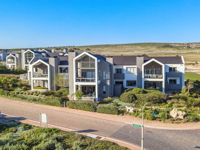 Aerial view of a modern townhouse complex featuring contemporary architectural design, tiled roofs, private balconies, and well-maintained landscaped gardens in a coastal setting.