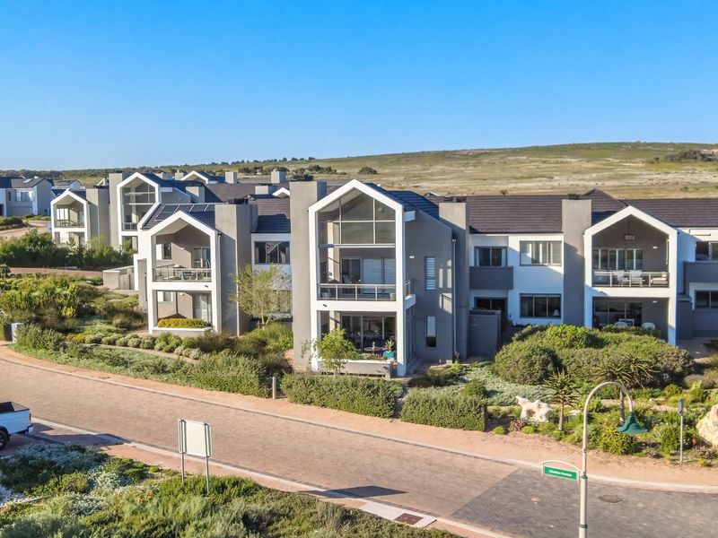 An aerial view of a modern townhouse complex featuring contemporary architectural design, tiled roofs, private balconies, and well-maintained landscaped gardens.