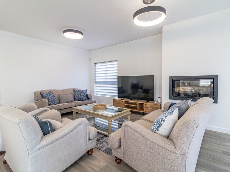 A bright and modern living room featuring a sleek built-in fireplace, recessed shelving, and contemporary lighting, finished with high-quality laminate flooring.