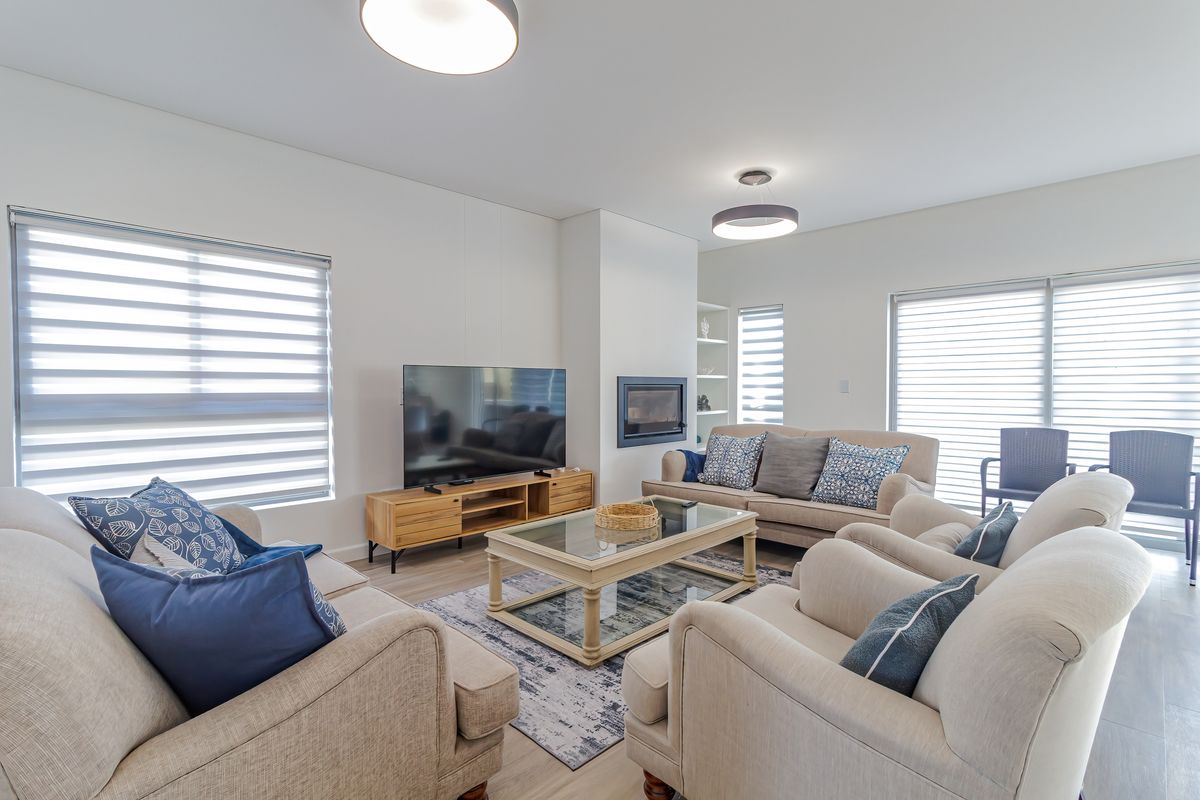 Bright and modern living room featuring a built-in fireplace, recessed shelving, and large sliding glass doors with roller blinds for natural light control.