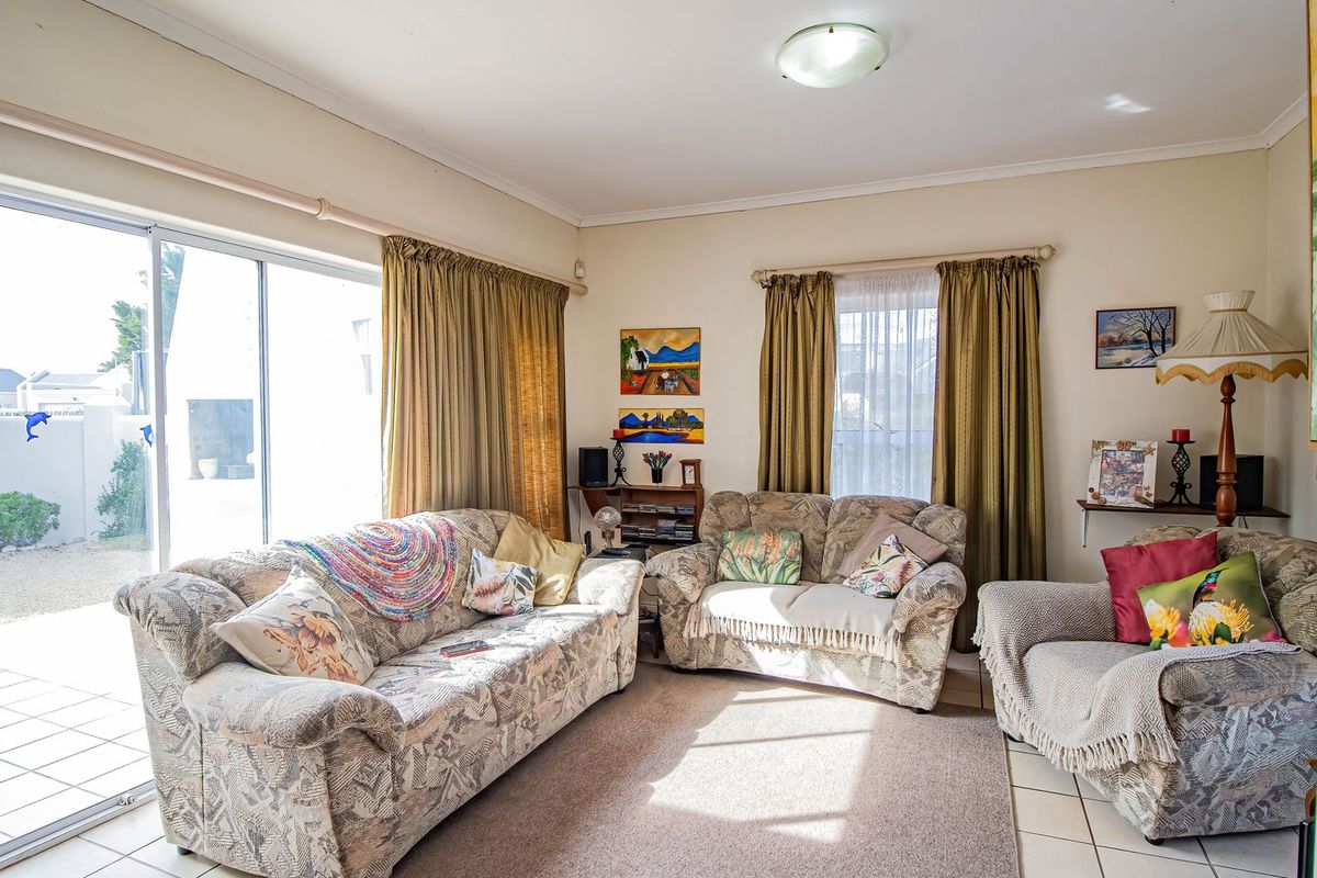 A living room featuring tiled flooring and a large sliding glass door providing access to the outdoor patio area.
