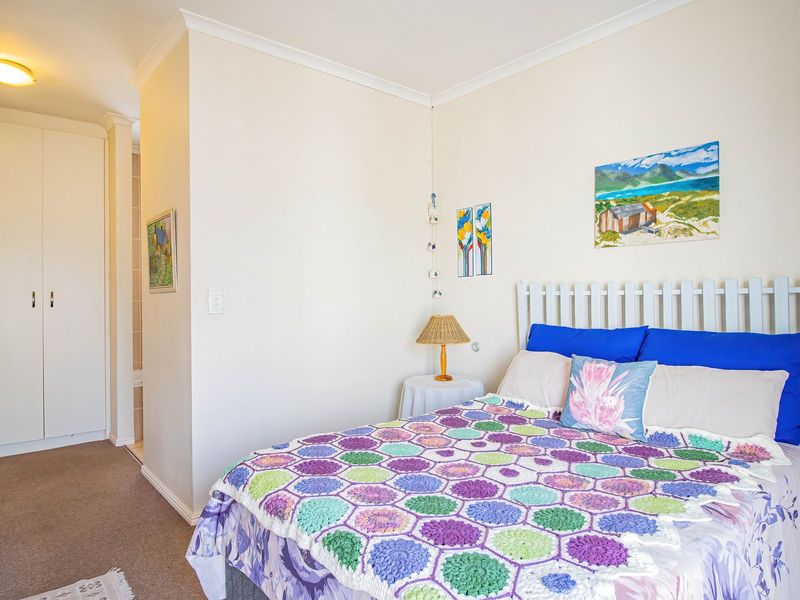 A functional bedroom featuring neutral walls, carpet flooring, and a built-in wardrobe with access to an adjoining space.