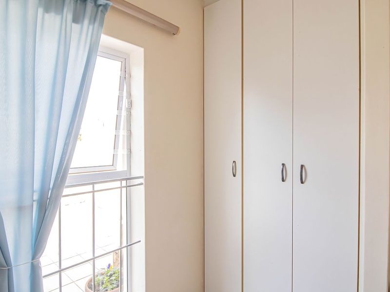 A bedroom interior featuring built-in cupboards and a window with a curtain rail.