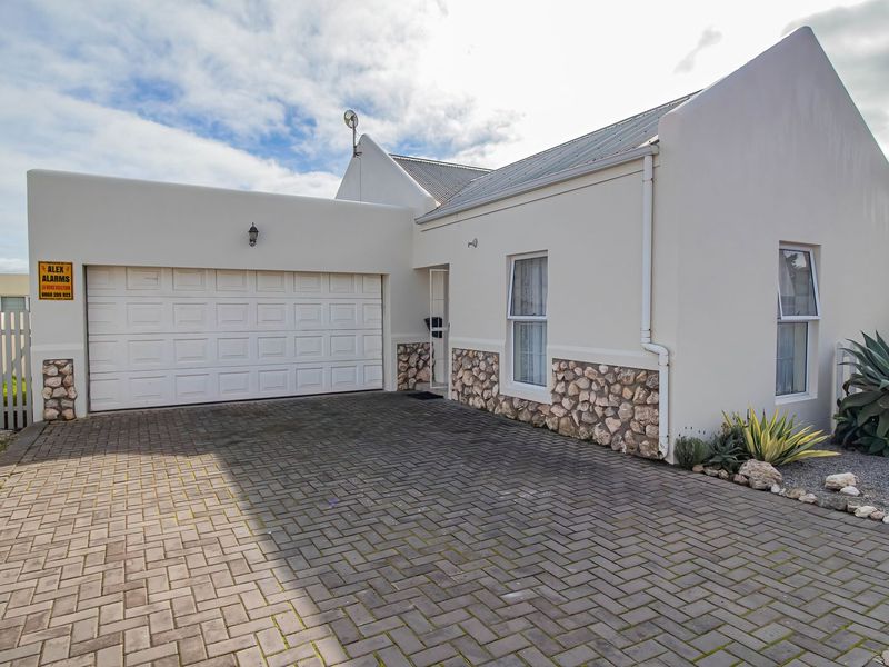Front elevation of a well-maintained house featuring a paved driveway, double garage, and decorative stone cladding accents.