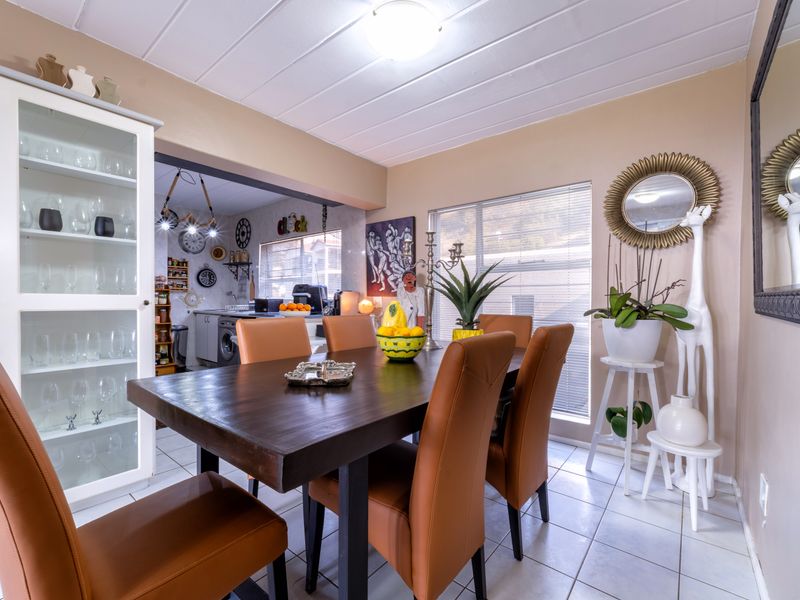 Open plan dining area featuring tiled flooring, a built-in display cabinet, and a seamless transition into the adjacent kitchen space.