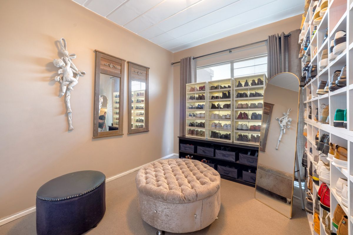 A well-organized dressing room or bedroom featuring extensive built-in shelving for storage and neutral wall finishes.
