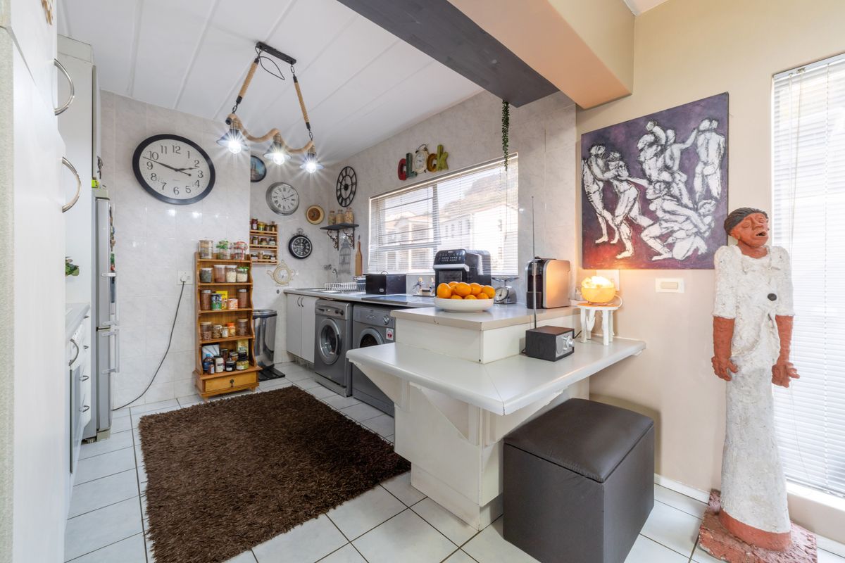 A functional kitchen area featuring tiled flooring, built-in cabinetry, and integrated laundry appliances, offering a practical layout for daily household tasks.