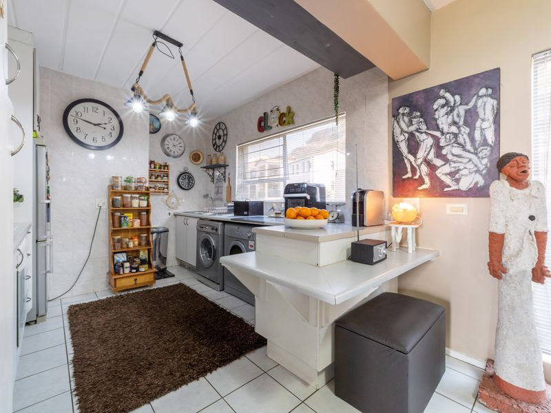A functional kitchen area featuring tiled flooring, built-in cabinetry, and integrated laundry appliances, offering a practical layout for daily household tasks.