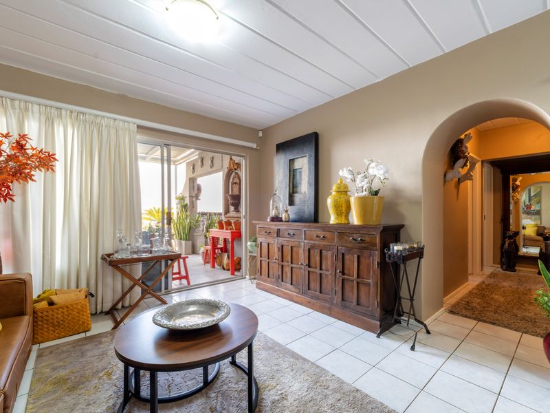A living room featuring tiled flooring, an arched entryway leading to a hallway, and a sliding glass door providing access to an outdoor patio area.