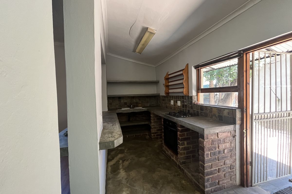 Rustic kitchen featuring brick base cabinetry, concrete countertops, built-in oven, gas hob, and direct access to the exterior via a security gate.