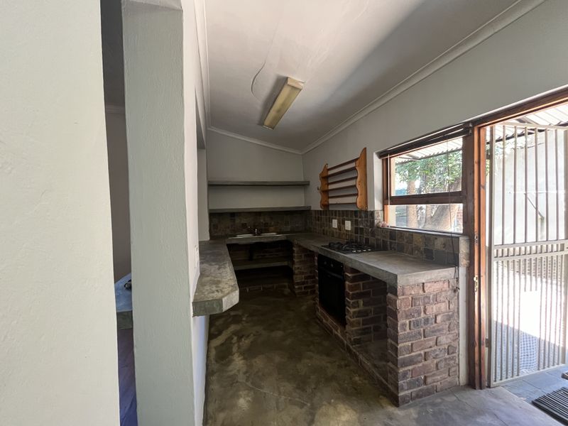 Rustic kitchen featuring brick base cabinetry, concrete countertops, built-in oven, gas hob, and direct access to the exterior via a security gate.