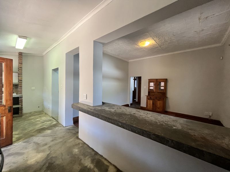 Open plan living area featuring a concrete breakfast bar, exposed brick fireplace, and textured ceilings, offering a blank canvas for renovation.