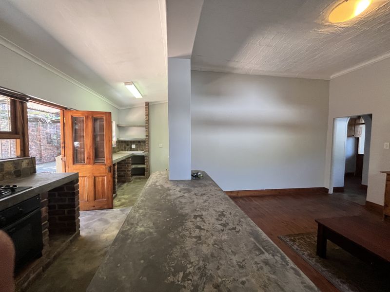 Open plan living and kitchen area featuring a rustic brick and concrete kitchen design with timber flooring and direct access to the exterior.