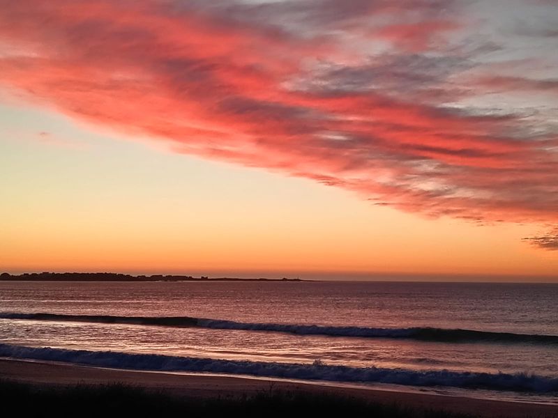 A scenic view of the ocean coastline at sunset, showcasing the natural landscape and horizon.