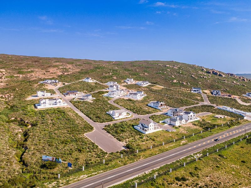 Aerial view of a residential estate development featuring multiple detached homes, paved internal roads, and surrounding natural landscape.