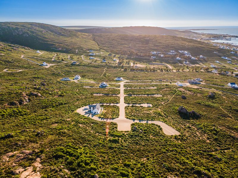 Aerial view of a coastal residential development featuring established road infrastructure and scenic landscape surroundings.