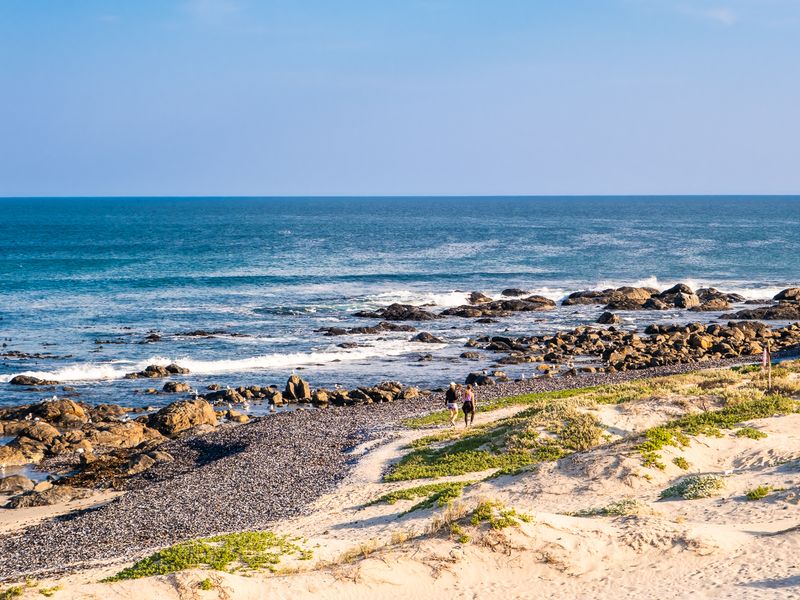 A scenic view of the rocky coastline and sandy dunes overlooking the ocean.