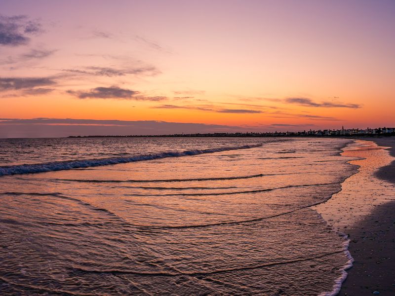 A scenic sunset view over the ocean and coastline, highlighting the natural landscape and beach setting of the property location.