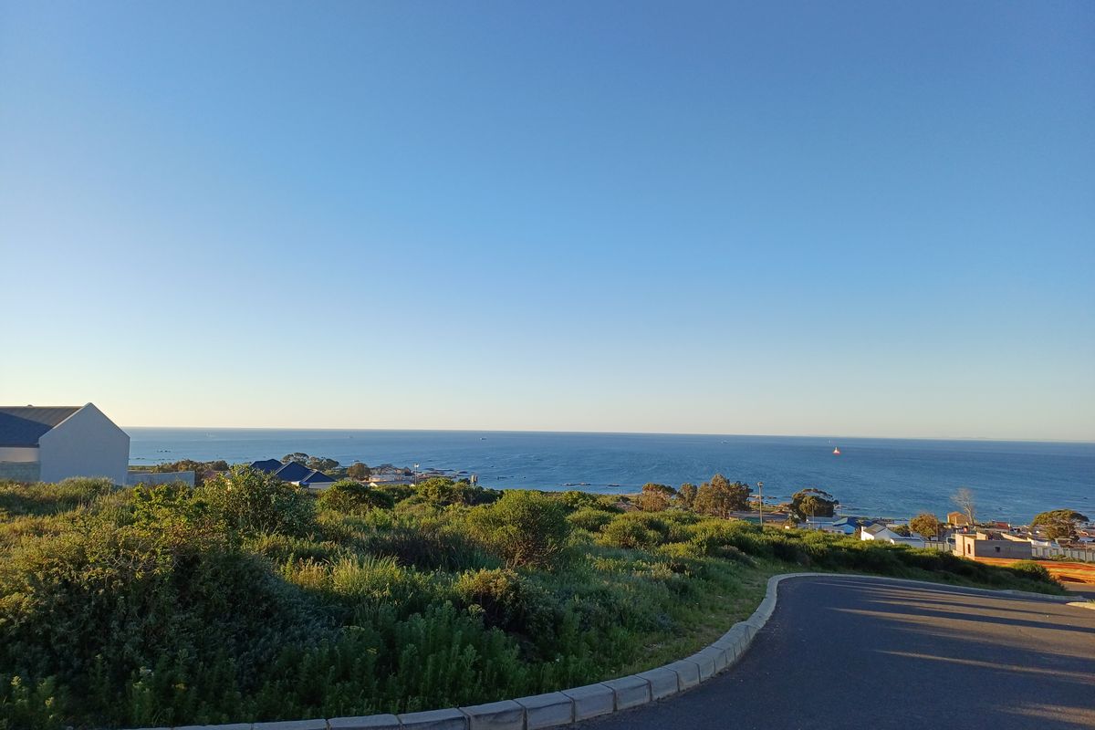 A scenic view overlooking the coastline and ocean from a paved residential street, showcasing the property's elevated position and coastal outlook.