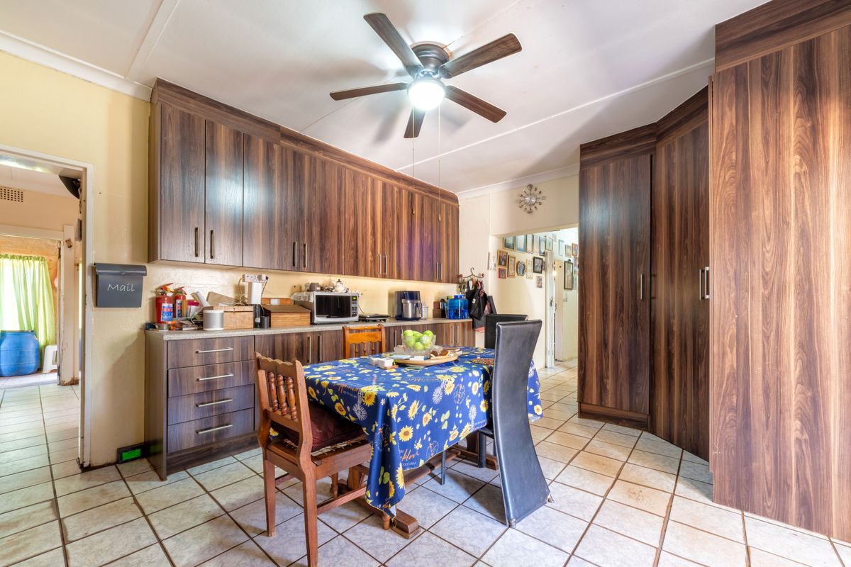 A functional kitchen featuring dark wood-look laminate cabinetry, tiled flooring, and a central ceiling fan, offering ample storage space.