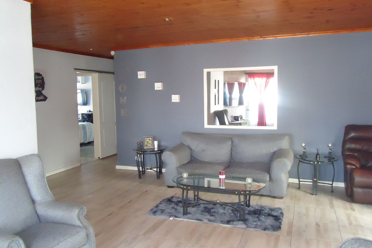 A living room featuring a timber ceiling, tiled flooring, and a unique internal window looking through to an adjacent space.