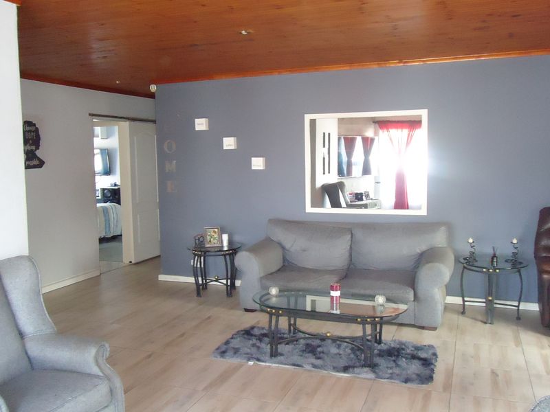 A living room featuring a timber ceiling, tiled flooring, and a unique internal window looking through to an adjacent space.