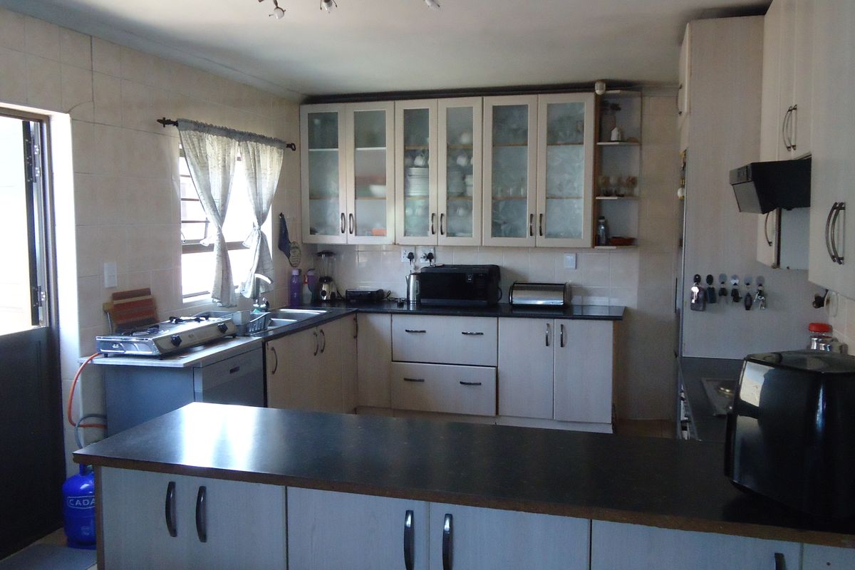 A functional kitchen featuring ample built-in cabinetry, dark laminate countertops, a tiled splashback, and an integrated extractor fan.