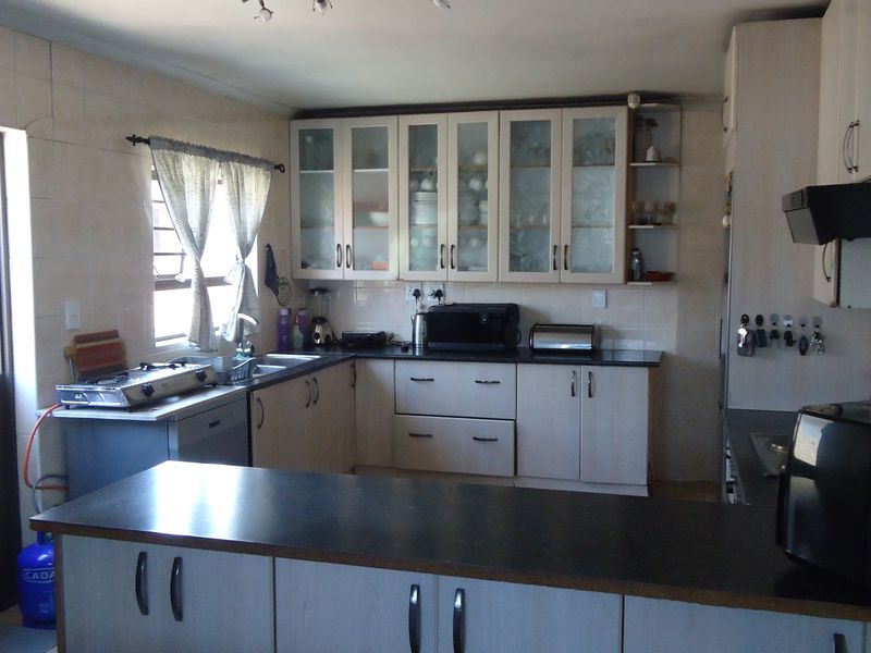A functional kitchen featuring ample built-in cabinetry, dark laminate countertops, a tiled splashback, and an integrated extractor fan.