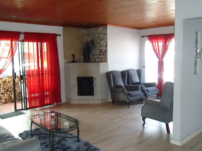 Spacious living room featuring a wood-paneled ceiling, tiled flooring, and a built-in fireplace, with sliding glass doors providing access to the outdoor area.