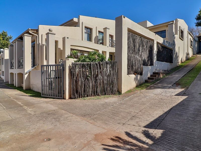 Front exterior view of a multi-level residential property featuring a concrete driveway, gated entrance, and stucco facade with balcony access.