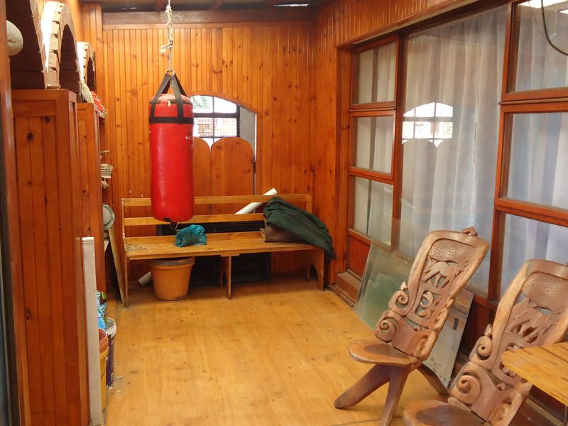 Enclosed patio area featuring extensive timber wall paneling and flooring, with large timber-framed windows and doors providing natural light.