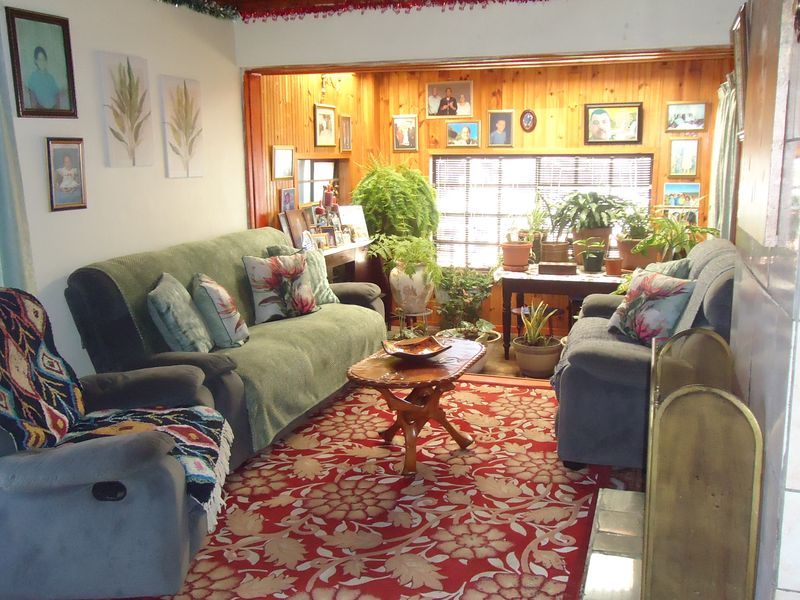 A living room featuring timber wall paneling and a tiled fireplace surround, offering a traditional aesthetic with potential for modernization.