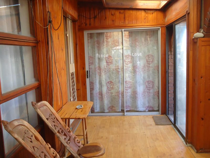 Enclosed patio area featuring extensive timber wall paneling, sliding glass doors, and a skylight, offering a rustic aesthetic with potential for modernization.