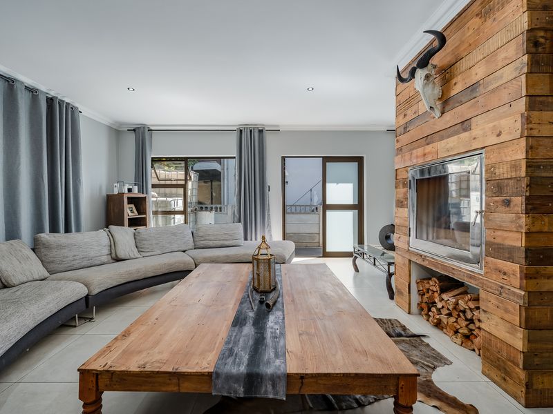 Spacious living room featuring a prominent reclaimed wood-clad fireplace, tiled flooring, and direct access to the outdoor area through sliding glass doors.