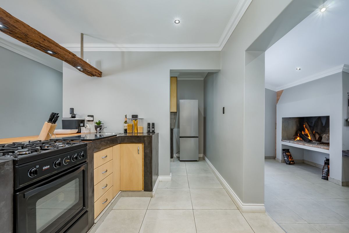 Modern kitchen featuring stone countertops, gas stove, and tiled flooring, with an adjacent living area showcasing a built-in fireplace.