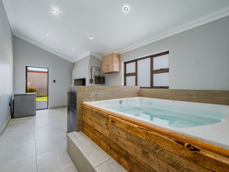 Spacious bathroom featuring a built-in bathtub with wood-look cladding, tiled flooring, recessed lighting, and a built-in fireplace, with direct access to the outdoor area.