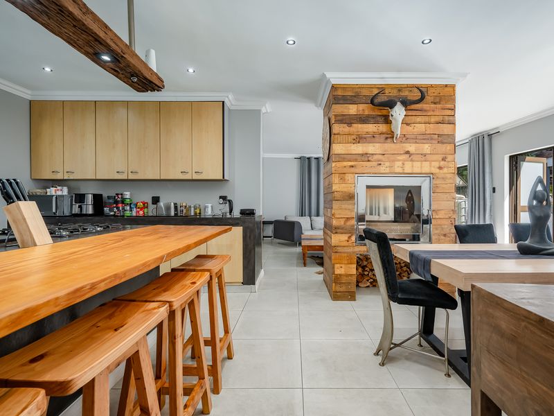 Spacious open-plan living area featuring a modern kitchen with timber breakfast bar and a striking central fireplace with timber cladding.