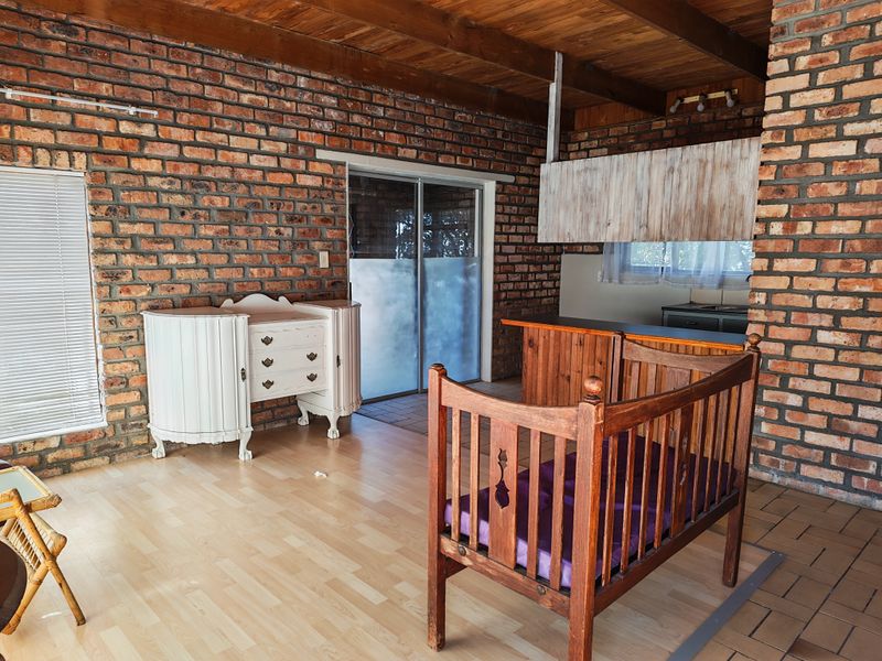Open plan living area featuring exposed brick walls, timber beam ceilings, and a functional kitchen space with integrated cabinetry.